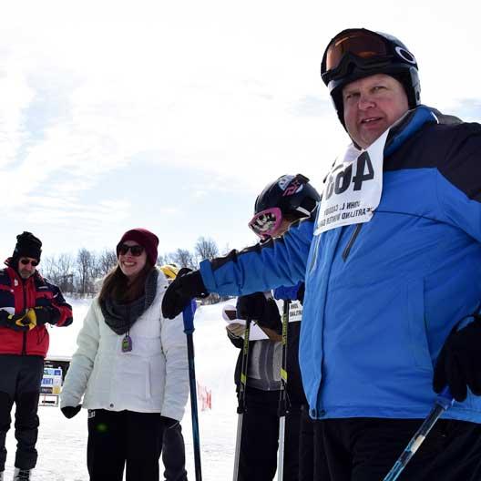A Special Olympics athlete in ski gear, with a Benedictine College student volunteer nearby